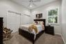 High-ceiling room featuring neutral carpeting, plantation shutter window coverings, and a ceiling-mounted fan with integrated lighting