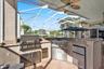 Covered patio featuring an integrated outdoor kitchen with stone countertops, stainless steel grill, stainless steel under-counter refrigerator, and a