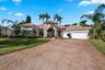 Stucco exterior featuring a tile roof, decorative arched entryway, patterned paver driveway, and an attached multi-car garage