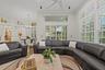 High ceilings featuring a multi-blade ceiling fan, expansive transom windows, built-in wall niches, custom plantation shutters, and sliding glass door