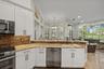 Kitchen featuring white shaker-style cabinetry, stone countertops, brick-tile backsplash, stainless steel appliances, and tile flooring