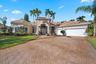Single-story residence featuring a tile roof, stucco exterior, arched entryway, stamped concrete driveway, and established palm landscaping