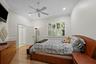 Room featuring crown molding, chair rail trim, wood-finish flooring, white plantation shutters, and a ceiling fan