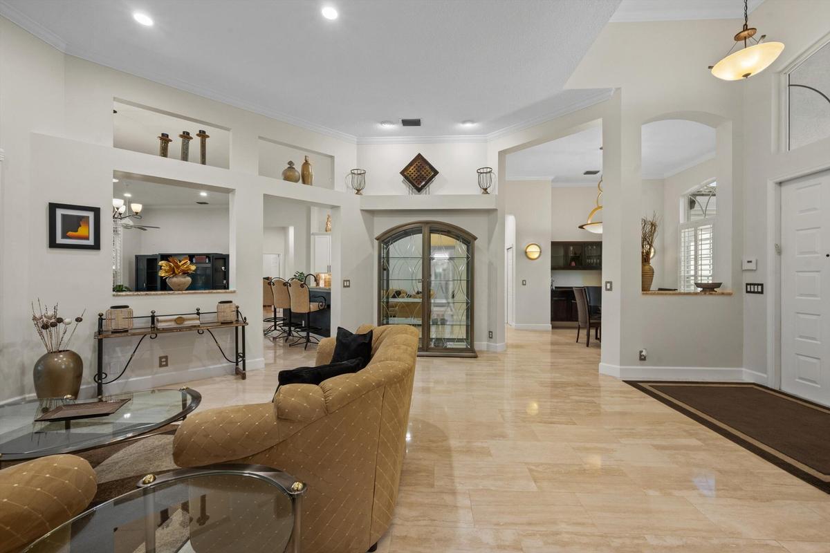 High ceilings featuring recessed lighting, polished stone flooring, built-in display niches, and an arched-top glass cabinet