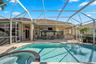 Screen-enclosed patio featuring a paver deck, built-in outdoor bar, in-ground pool, and integrated spa