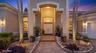 Stucco exterior featuring an arched entryway, double-door entrance, transom window, and paver walkway