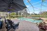 Screened-in pool area featuring a built-in spa, paver patio, and metal enclosure