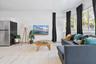 Open-concept area featuring light-toned tile flooring, recessed window bay, and stainless steel refrigerator