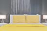 Bedroom featuring a charcoal accent wall, a white headboard with yellow bedding, and matching bedside lamps