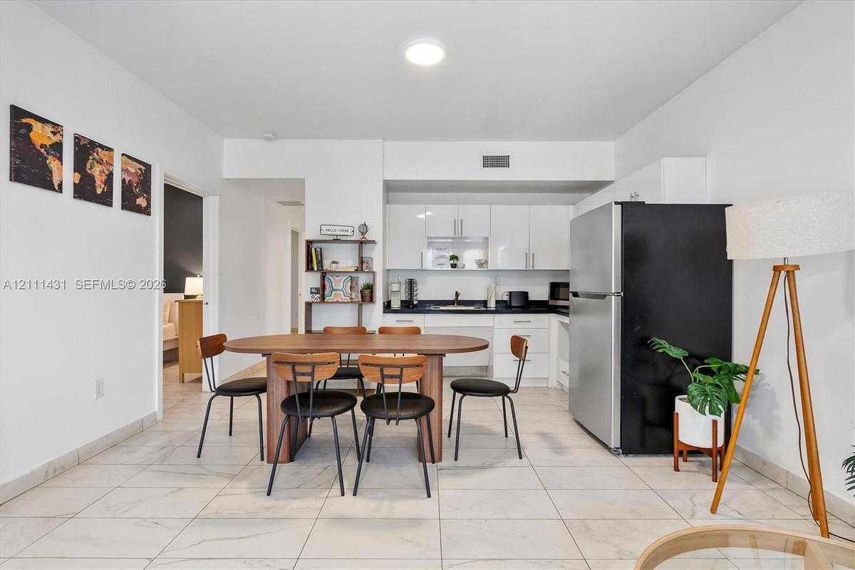 Kitchen featuring white high-gloss cabinetry, dark stone-surface countertops, and large-format tile flooring