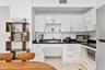 Kitchen featuring white high-gloss cabinetry, dark countertops, integrated stainless steel microwave, and tiled flooring