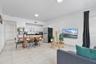 Open-concept floor plan featuring light-toned tile flooring, white cabinetry, dark countertops, and recessed lighting