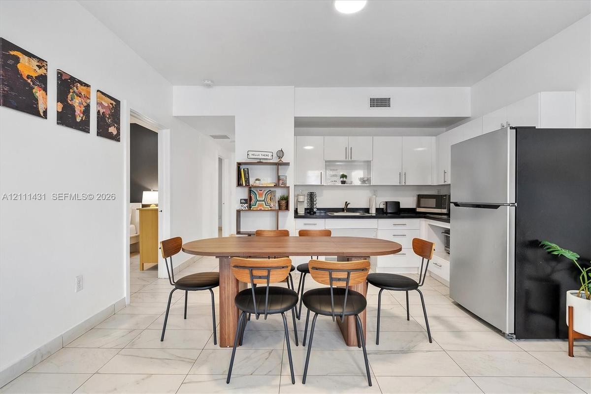Kitchen featuring white cabinetry, solid-surface countertops, and stainless steel refrigerator, complemented by tile flooring