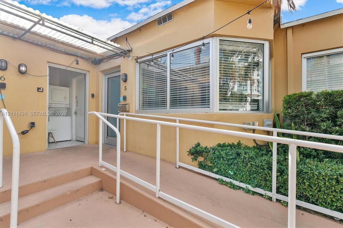 Exterior entryway featuring a concrete ramp with white railings, a bay window, and a covered patio area