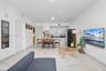Open-concept interior featuring large-format tile flooring, recessed lighting, and a kitchen equipped with white cabinetry and dark countertops