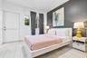 Bedroom featuring large-format tile flooring, a charcoal accent wall, and a window with horizontal blinds