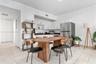 Kitchen featuring white shaker-style cabinetry, black stone countertops, stainless steel refrigerator, and light-toned tile flooring