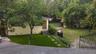 Stucco exterior dwelling featuring a multi-panel wood door, concrete paver pathway, artificial turf lawn, and ornamental metal fencing