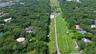 Aerial view of an expansive parcel featuring dense tree coverage, a linear stretch of open green space, and a paved path