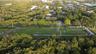 Expansive rectangular parcel featuring open terrain, mature perimeter trees, and a paved road frontage