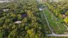 Aerial perspective of expansive wooded acreage featuring mature canopy coverage and cleared grassy terrain