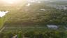 Aerial perspective of a sprawling parcel featuring expansive green space, mature tree canopy, and established landscaping