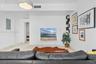 Living space featuring large-format tile flooring, a wall-mounted floating wood shelf, and black corner-mounted shelving