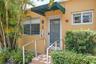 Exterior entrance featuring a concrete stoop with metal handrails, a glass-panel entry door, an integrated green fabric awning, and dual-pane windows