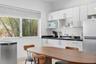 Kitchen featuring white cabinetry, dark stone-finish countertops, stainless steel refrigerator, and horizontal blind-covered windows