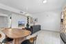 Open-concept interior featuring light-toned tile flooring, recessed ceiling lighting, a modern dome pendant fixture, and a wall-mounted floating shelf