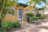 Stucco exterior featuring dual-pane windows, metal door awnings, concrete walkway, and built-in metal handrails