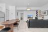 Open floor plan featuring large-format tile flooring, a modern dome-style pendant light, and built-in corner shelving