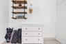 Wall-mounted industrial-style shelving featuring wood-finish tiers and matte black metal piping, white cabinetry, and a wall-mounted metal garment rai