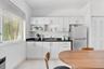 Kitchen featuring white cabinetry, dark countertops, tile flooring, stainless steel refrigerator, and horizontal window blinds