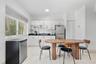 Kitchenette featuring white slab-panel cabinetry, black solid-surface countertops, recessed lighting, and white stone-finish tile flooring