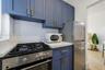 Kitchen featuring blue cabinetry with metallic hardware, light-toned countertop, white subway tile backsplash, and stainless steel gas range