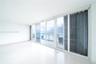 Floor-to-ceiling glass sliding doors, polished tile flooring, and a private balcony featuring a metal railing