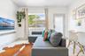 Living area featuring white tile flooring, a wall-mounted floating shelf, and a glass-paneled exterior door