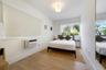 Room featuring wood-finish flooring, a wall-mounted climate control unit, a recessed window, a flush-mount globe light fixture, and a full-length wall