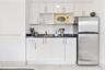 Kitchenette featuring white slab-panel cabinetry, dark stone-finish countertops, stainless steel refrigerator, and ceramic tile flooring
