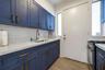 Kitchen featuring navy blue Shaker-style cabinetry, matte gold hardware, white subway tile backsplash, solid-surface countertops, and wood-finish floo
