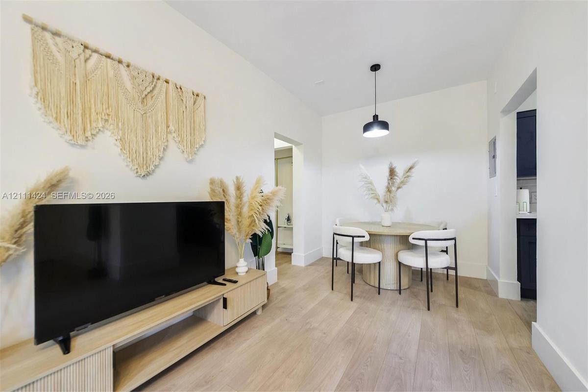 Neutral interior space featuring wood-finish flooring, crisp white walls, and a contemporary matte black pendant light fixture