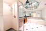 Enclosed shower with handheld fixture, built-in soaking tub, wood-finish cabinetry, stone countertop, and geometric mirrored ceiling accent