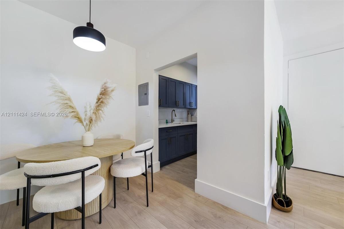 Wood-finish flooring, custom dark-toned cabinetry, stainless steel faucet, and black drum pendant lighting