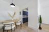 Wood-finish flooring, custom dark-toned cabinetry, stainless steel faucet, and black drum pendant lighting