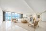 Open-concept interior featuring polished tile flooring, floor-to-ceiling glass panel sliding doors, and a private balcony