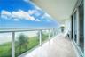 Covered balcony featuring stone tile flooring and a glass railing, encompassing water scenery