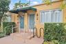 Exterior facade featuring stucco siding, metal-frame glass entry doors, green metal awnings, and metal handrails