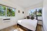 Bright room featuring wood-finish flooring, dual-aspect windows, and a wall-mounted air conditioning unit