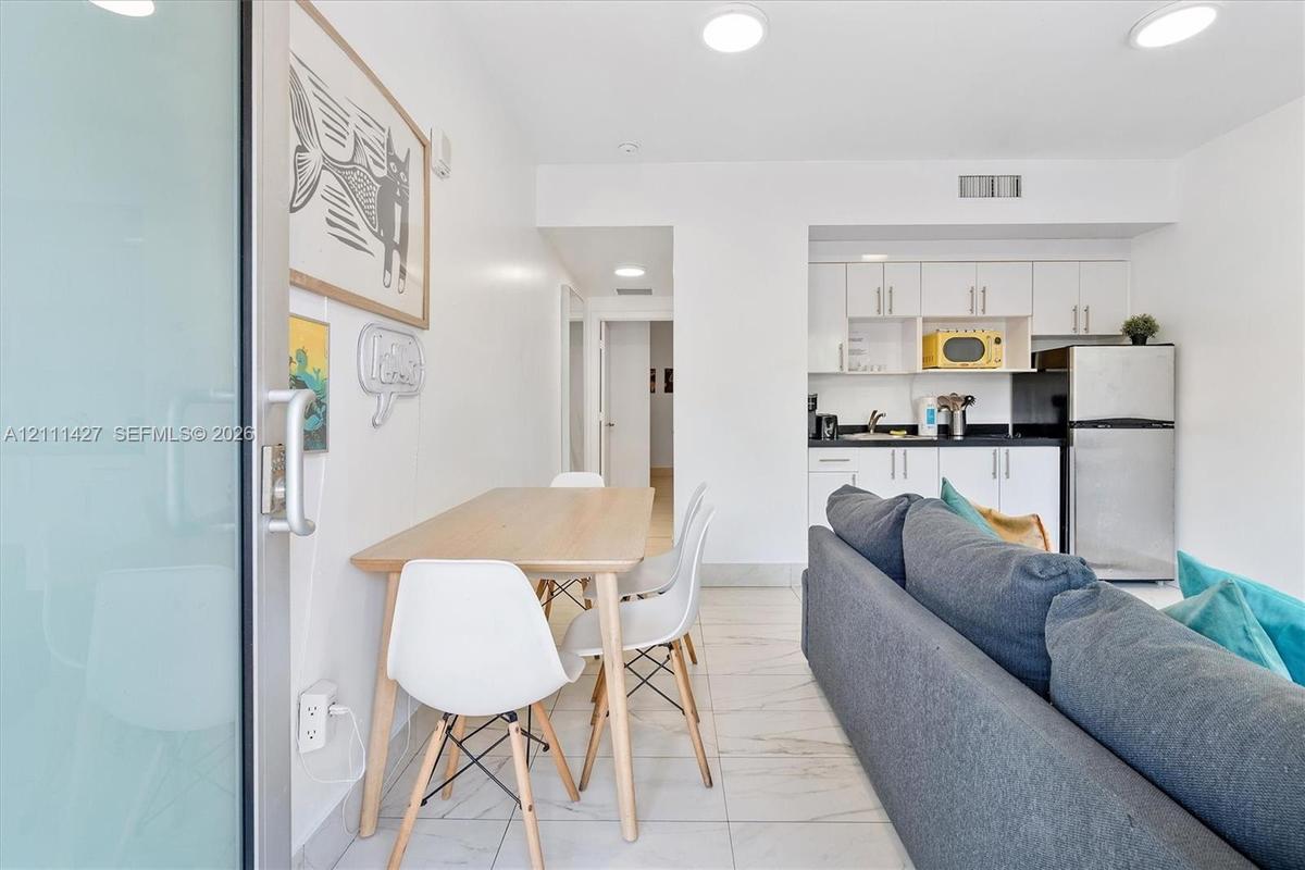 Kitchen featuring white cabinetry, solid-surface countertops, and stainless steel refrigerator, complemented by tile flooring and recessed lighting